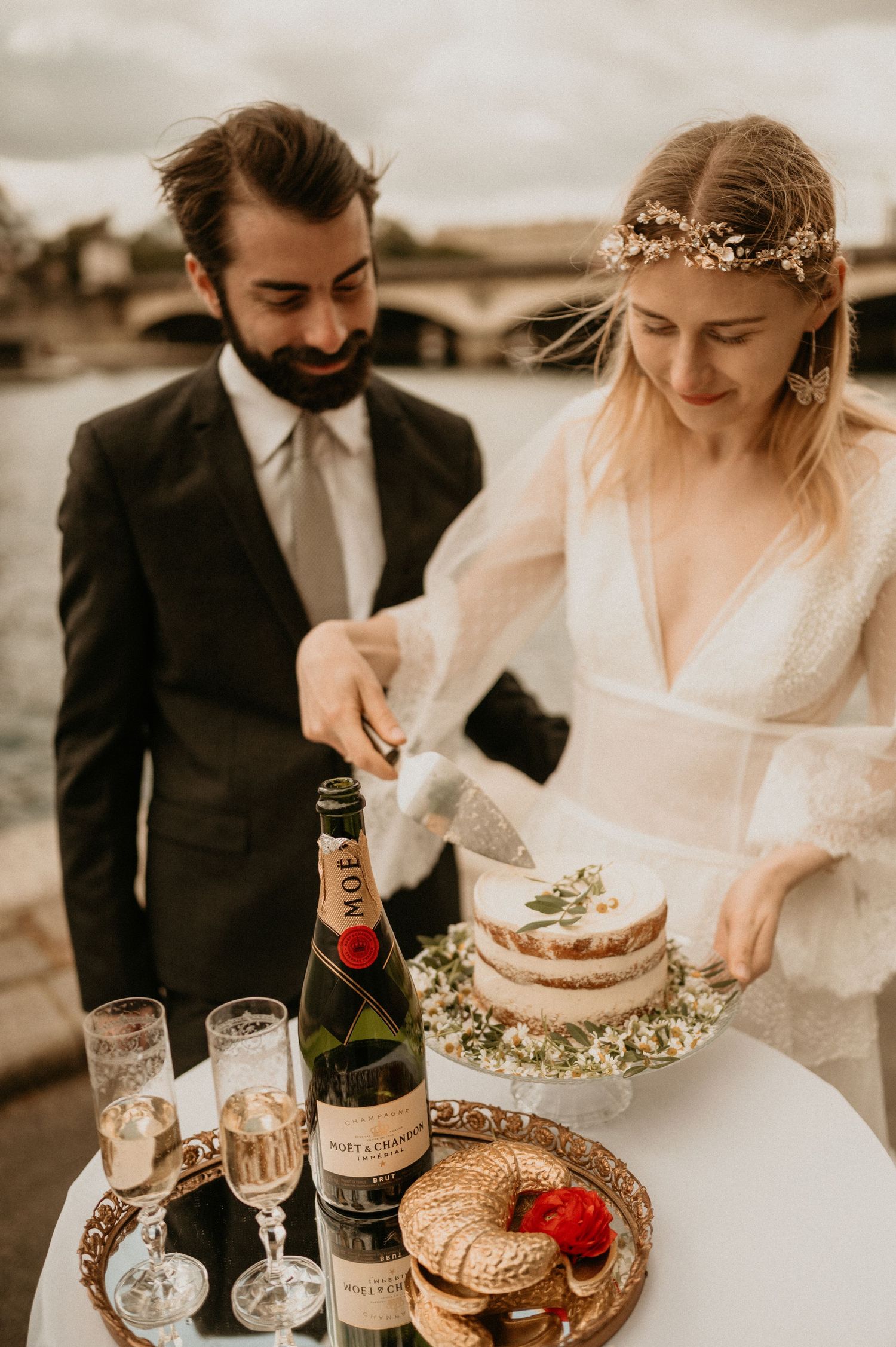 A wedding couple serves champagne and cake during their Paris celebration.