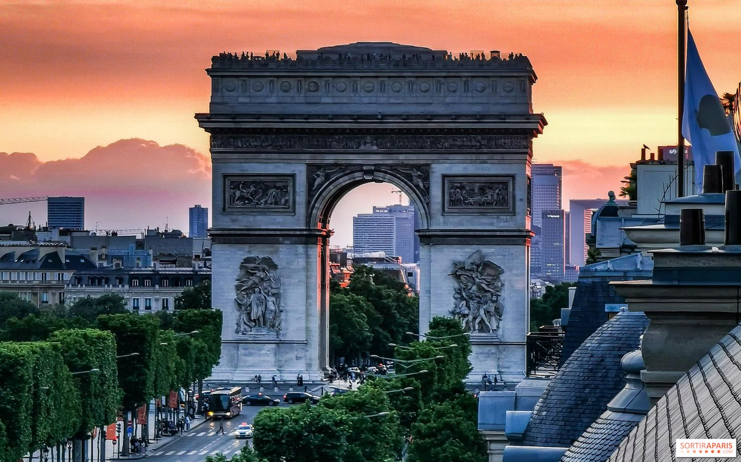 The Arc de Triomphe in Paris silhouetted against a dramatic orange sunset sky.