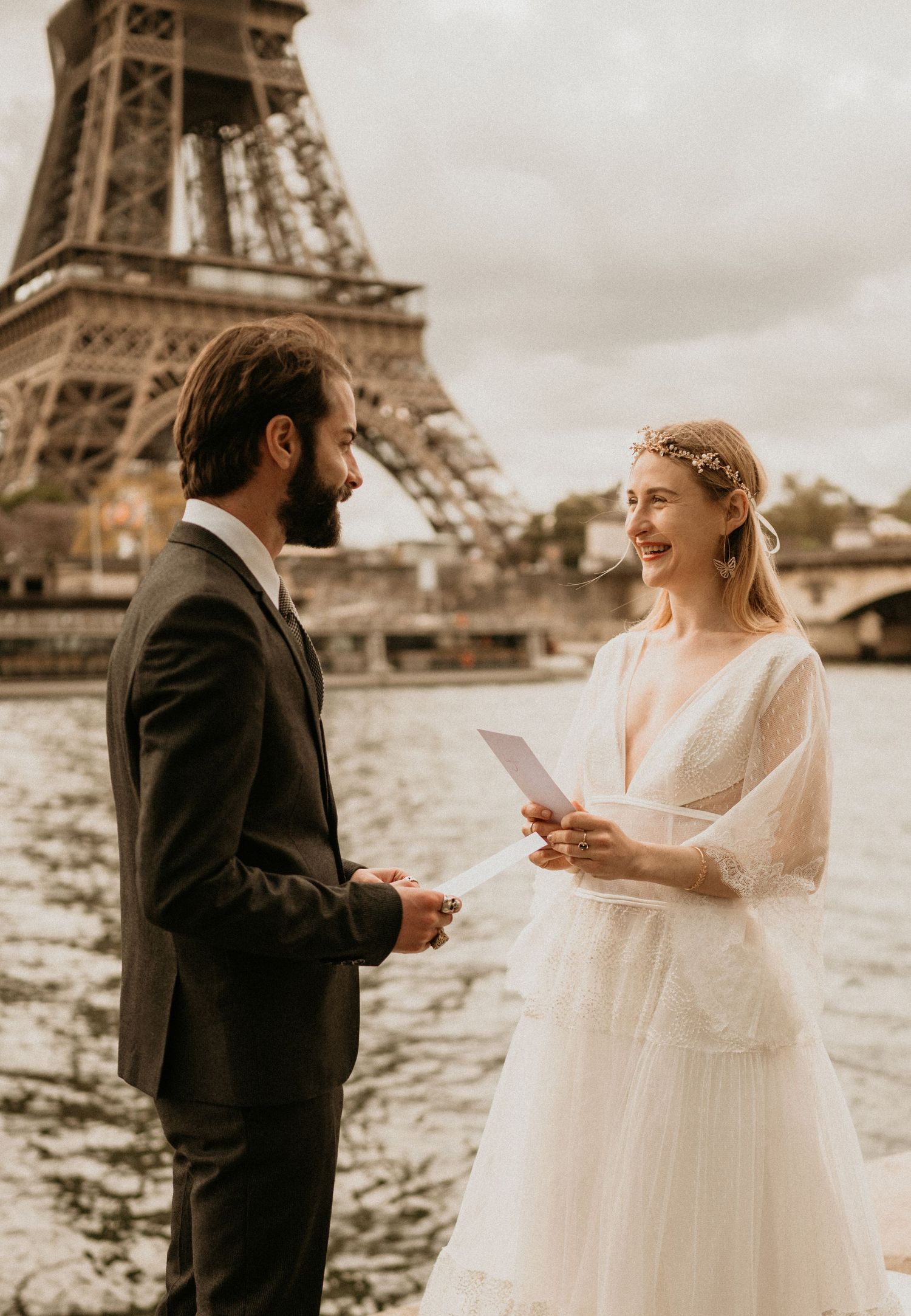 Romantic wedding ceremony by Seine River as couple reads vows near Eiffel Tower.