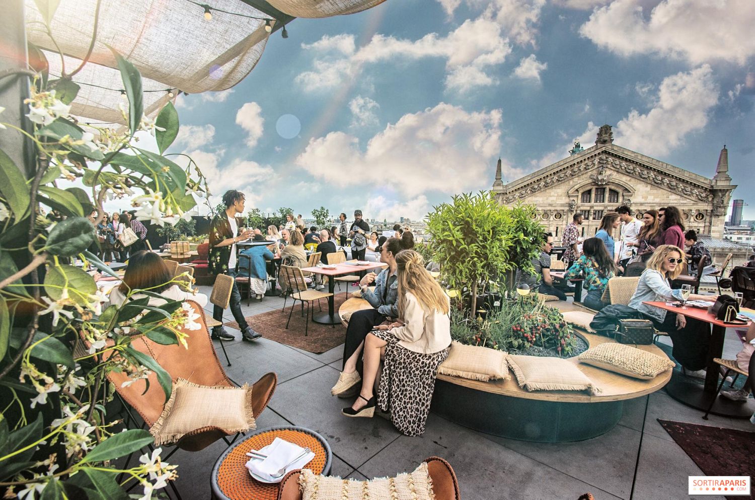 Rooftop terrace cafe in Paris with lush plants and views of the city.