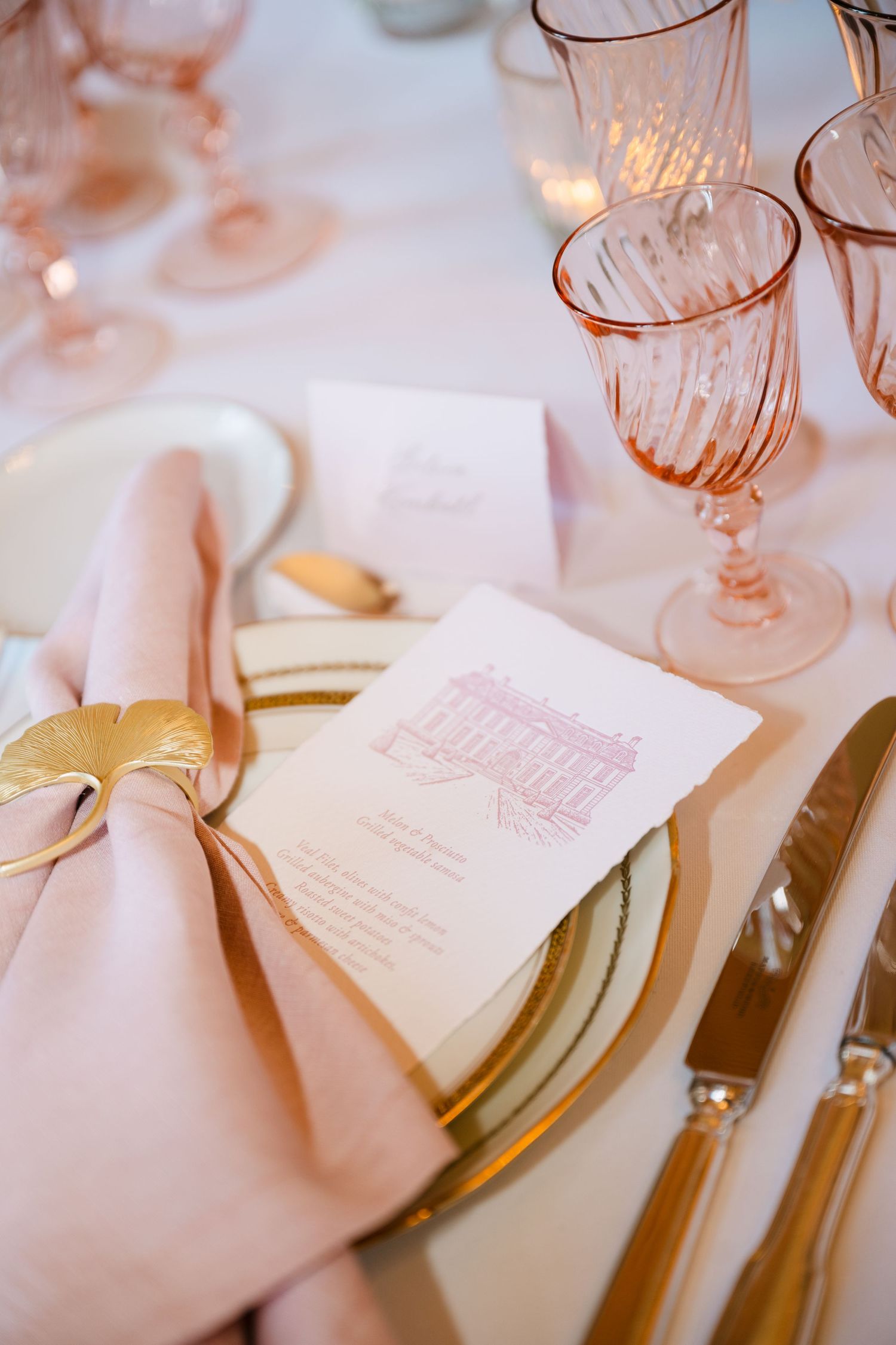 Elegant pink wedding table setting with gold charger plates, blush napkins, and rose-tinted glassware.
