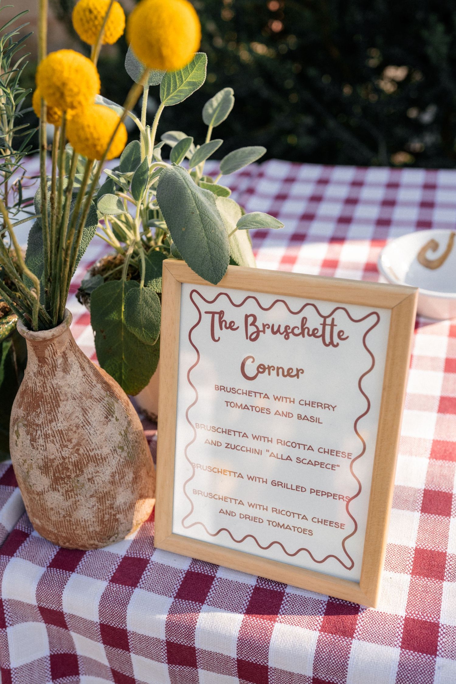 Bruschette corner menu sign on red checkered tablecloth with yellow flowers at Italian wedding.