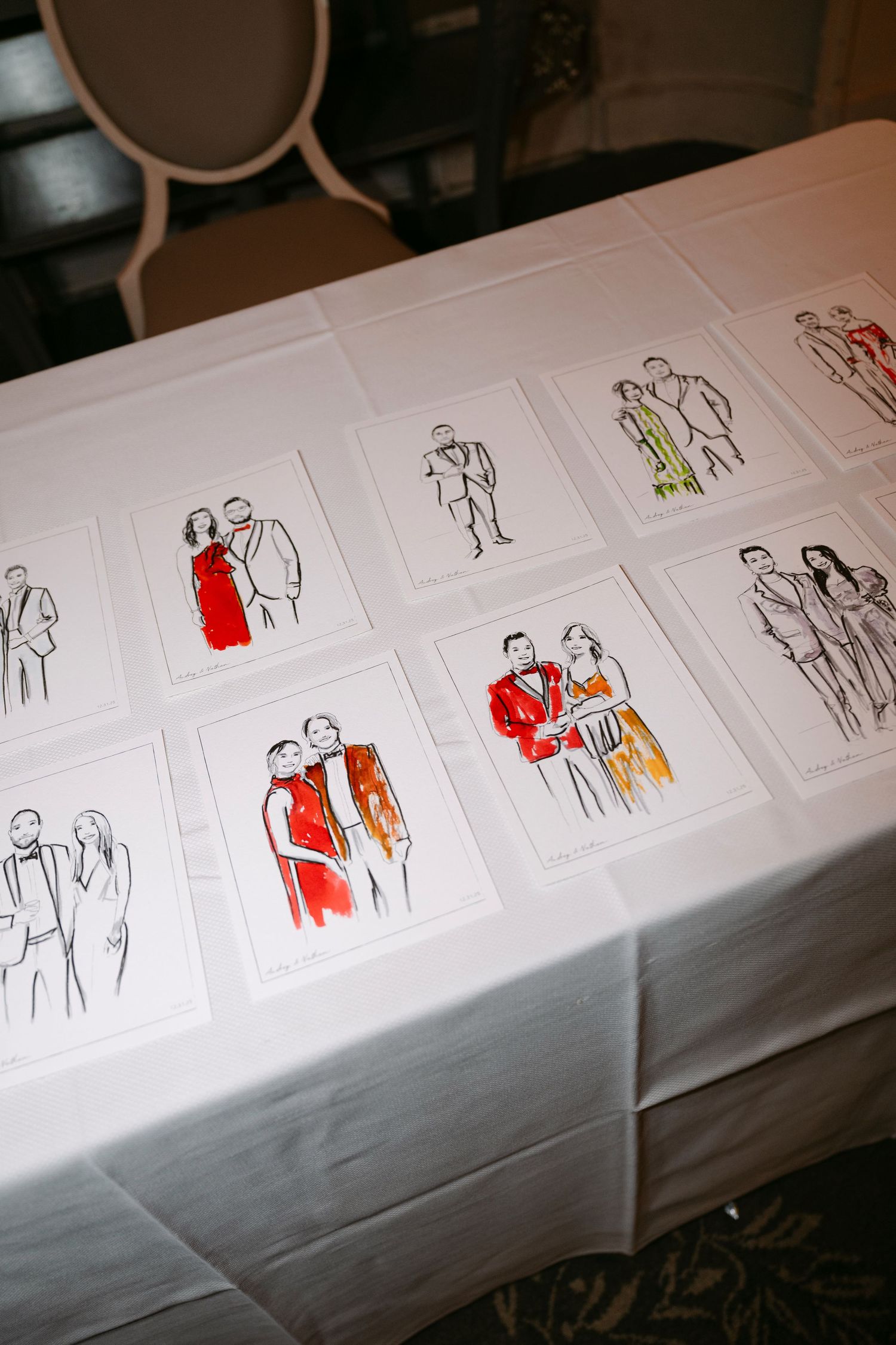 Live wedding sketches displayed on white tablecloth showing couples in colorful ink illustrations.