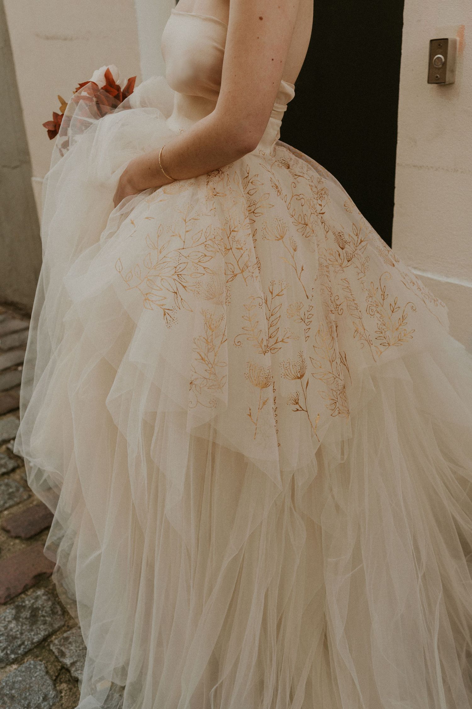Detail shot of a flowing tulle wedding dress with intricate floral embroidery.