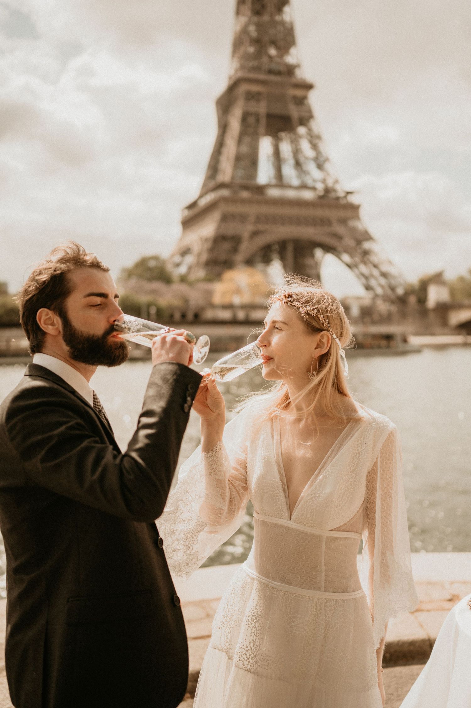 Couple toasts with champagne glasses in front of the Eiffel Tower during their Paris wedding.