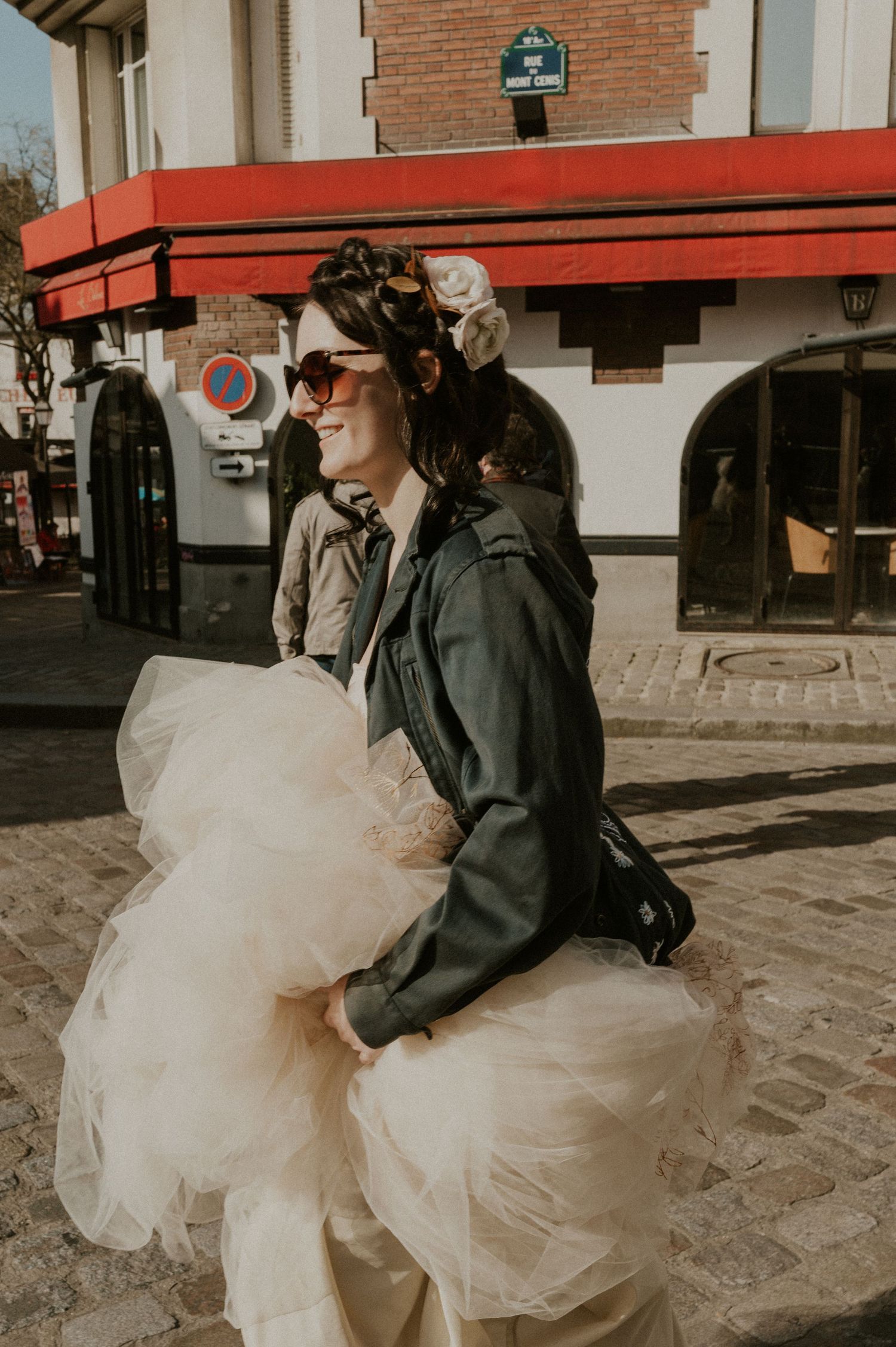 A fashionable look featuring a leather jacket paired with a flowing white tulle skirt on a cobblestone street.