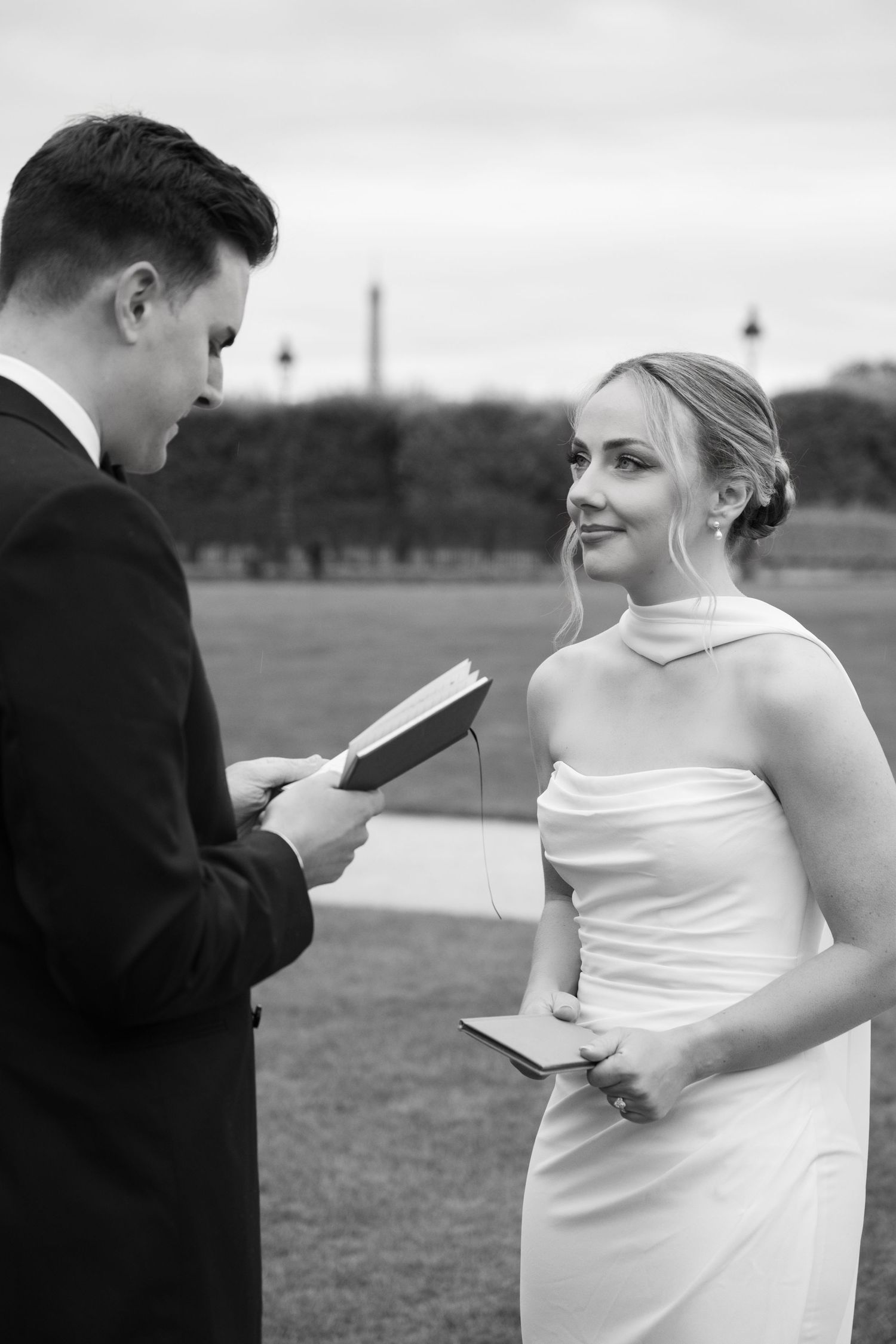 A black and white series of photos showing a couple reading letters to each other during an outdoor wedding ceremony.