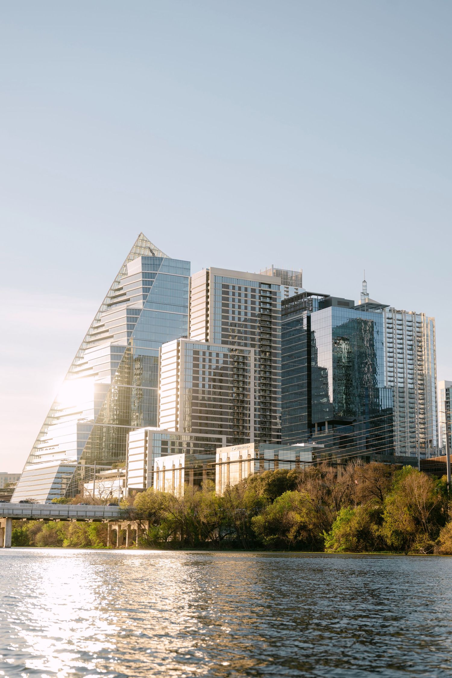 Modern glass skyscrapers along Austin Texas waterfront reflecting golden sunset light.