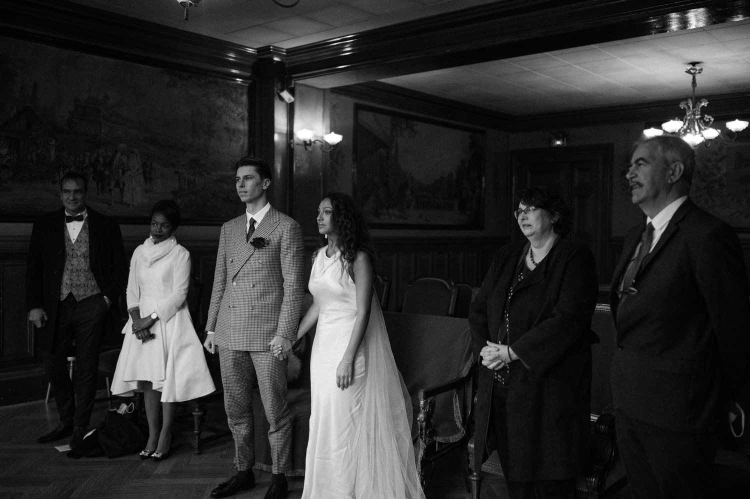 A black and white photo of a wedding party line-up in formal attire.