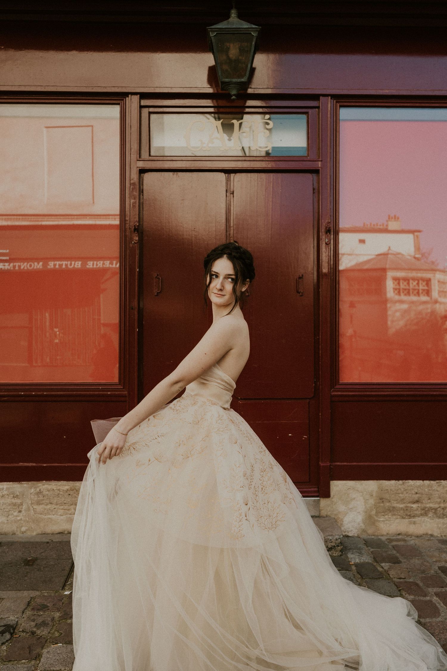 Sunset-lit bridal portrait highlighting delicate lace details against rustic French building.