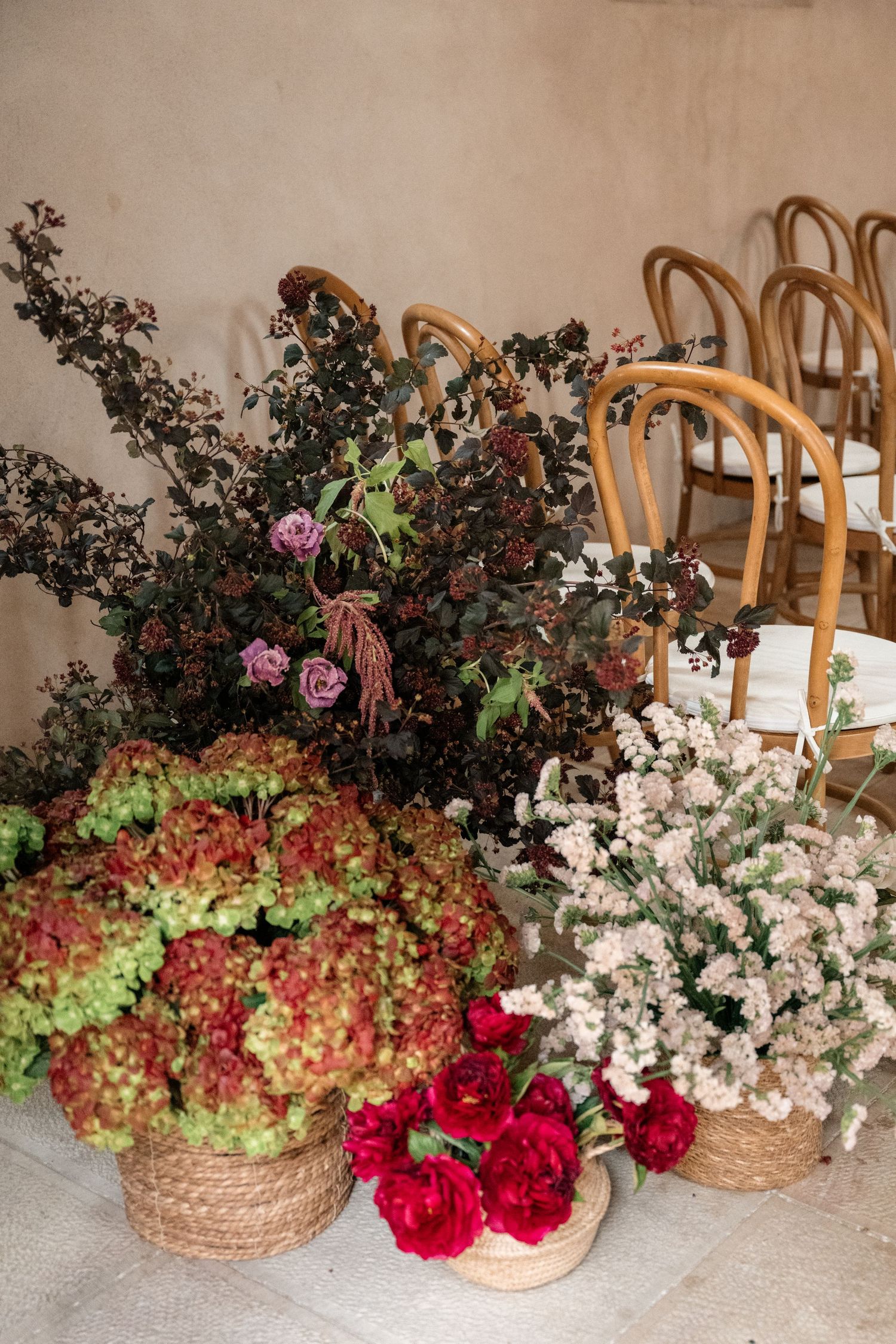 Beautiful floral arrangements in woven baskets featuring red roses, white flowers, and greenery against a light backdrop.