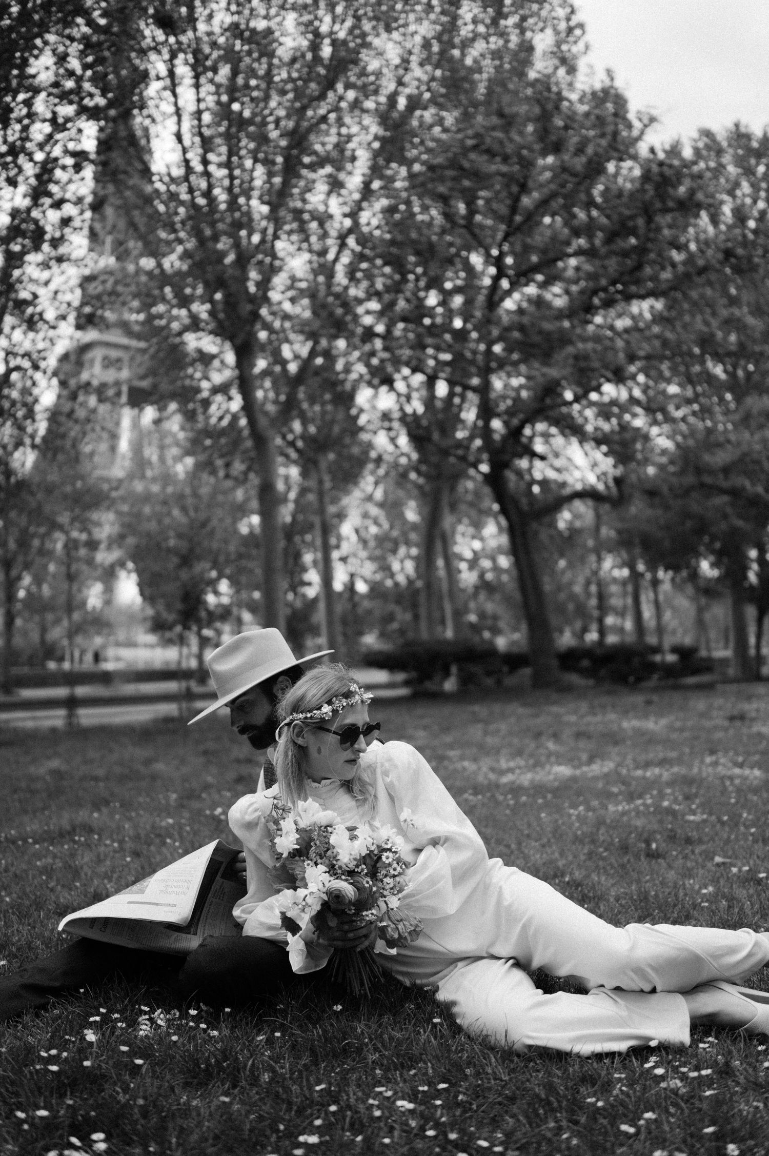 Black and white portrait in Parisian park with Eiffel Tower visible through trees.