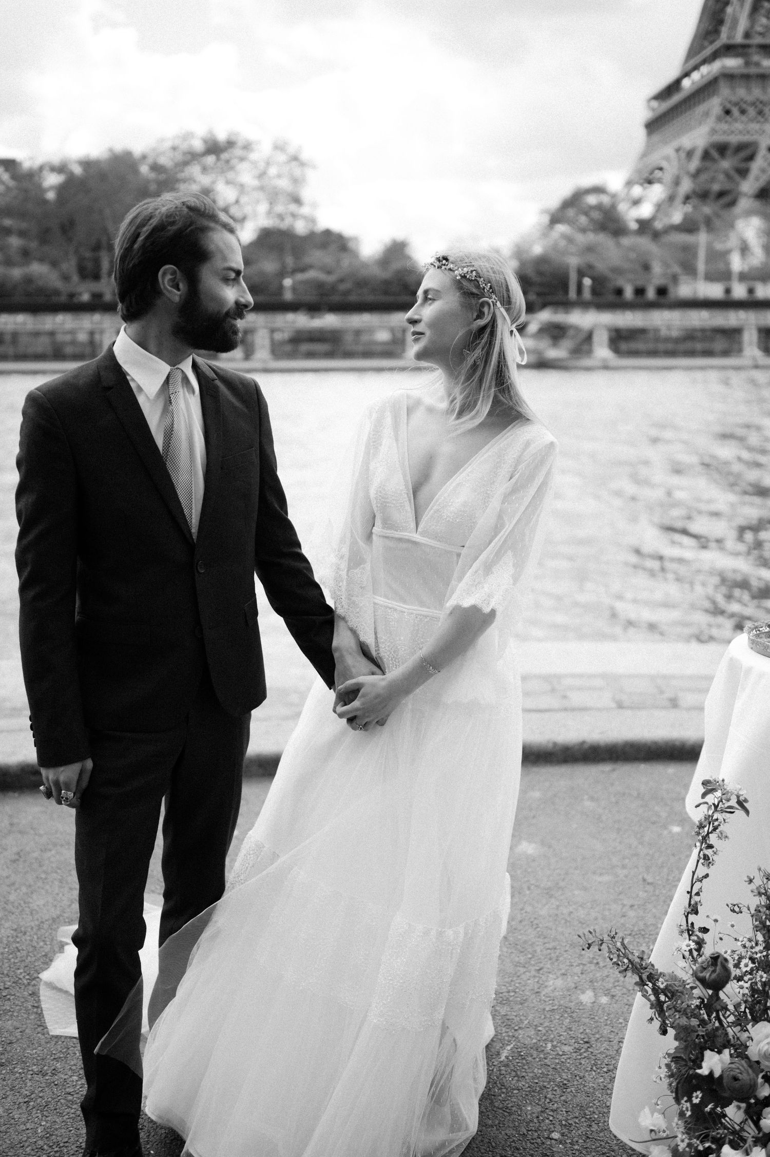 Elegant wedding couple poses near Eiffel Tower in Paris with bride in flowing white gown.
