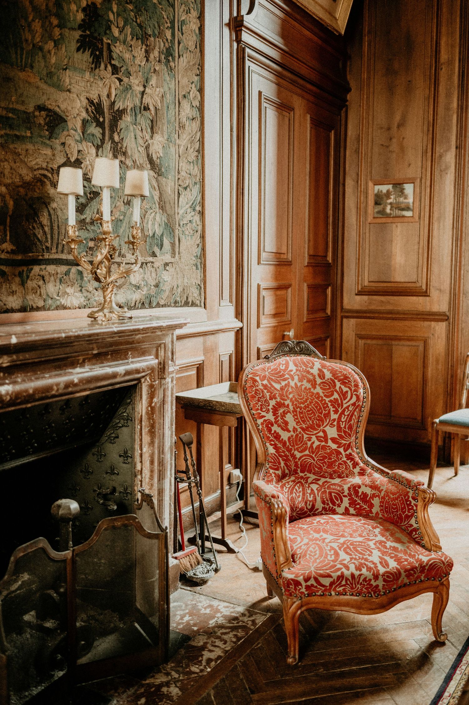Luxurious French interior with marble fireplace and red upholstered armchair.