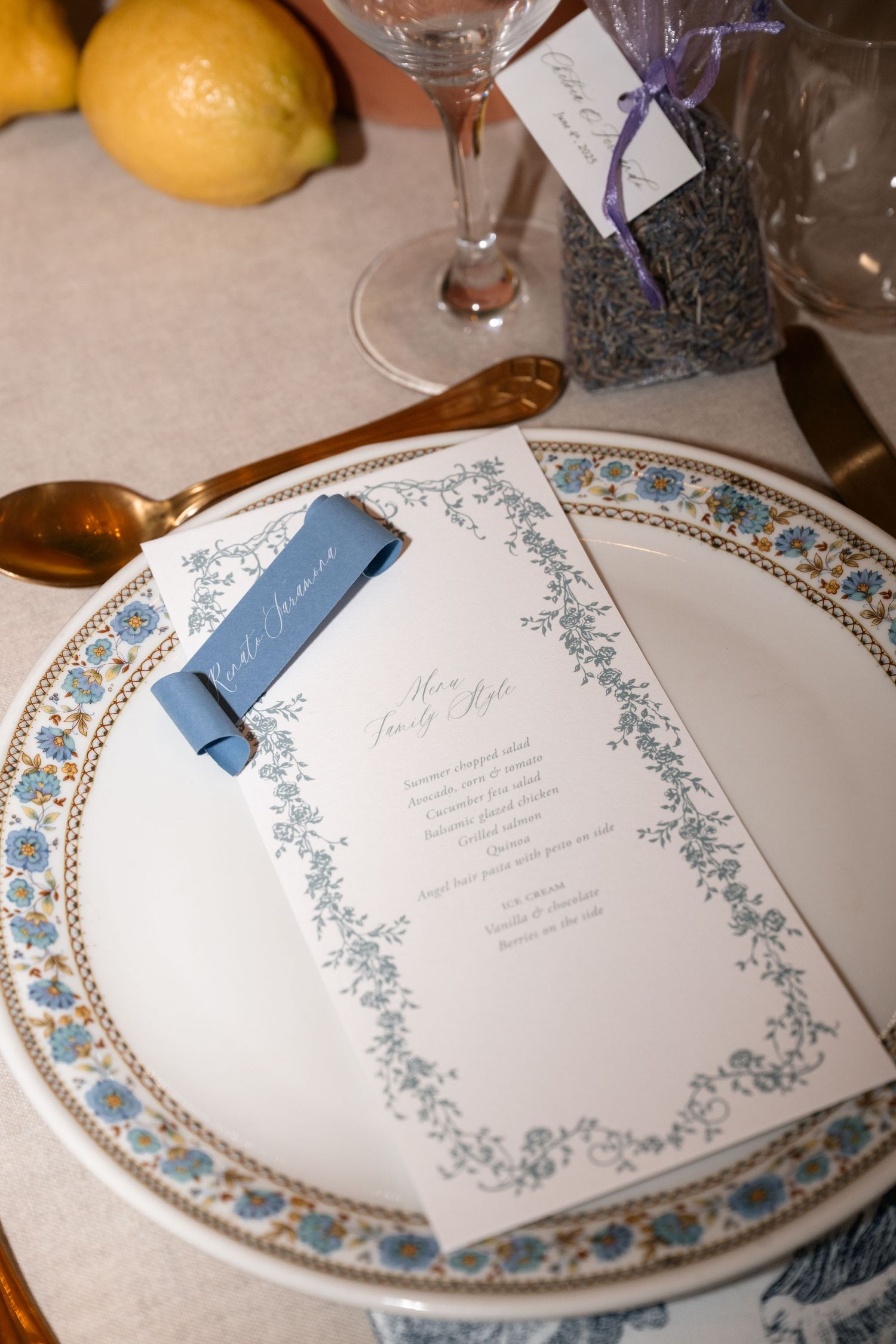 Ornate china plates with blue and silver floral borders displayed alongside elegant menu cards at place settings.