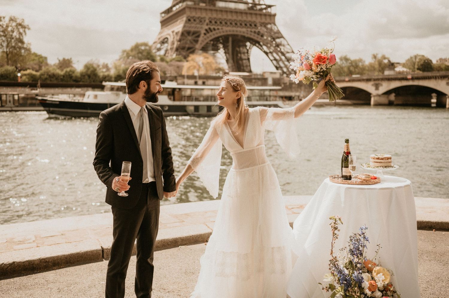 Couple celebrates their wedding day with champagne by the Seine River in Paris.