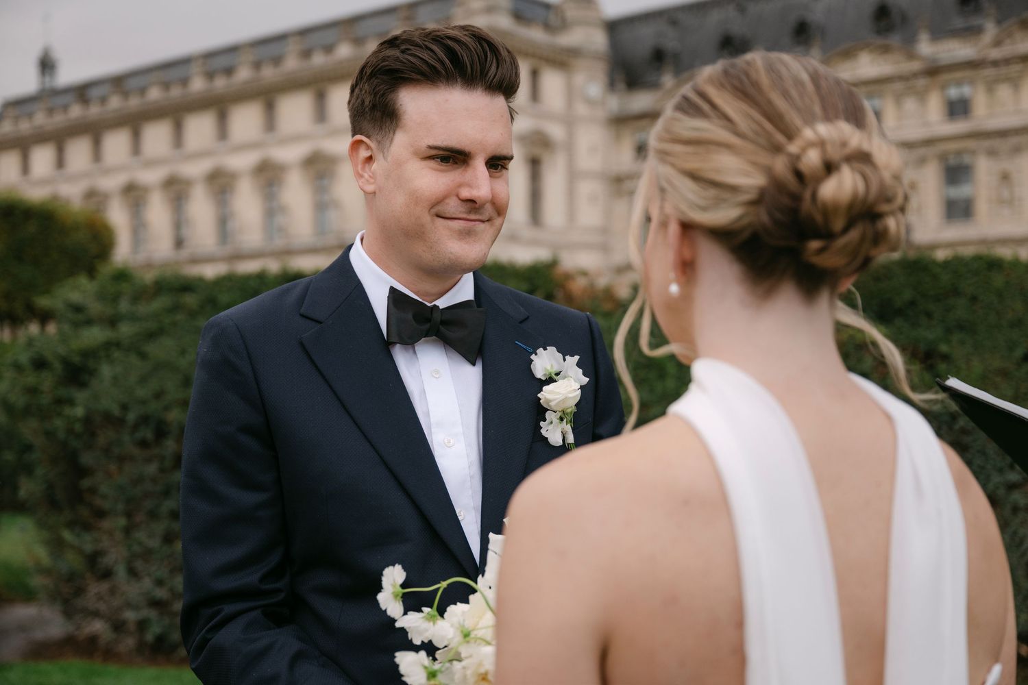 Elegant wedding couple shares romantic moments in front of a historic European palace.