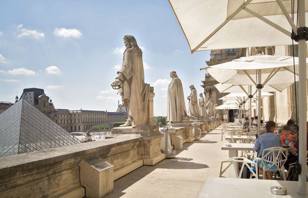 Historic statues line a terrace overlooking the Louvre Museum in Paris.