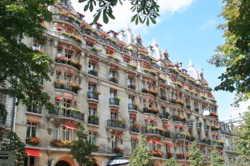 Historic Parisian building with ornate architecture and red-flowered balconies along its facade.