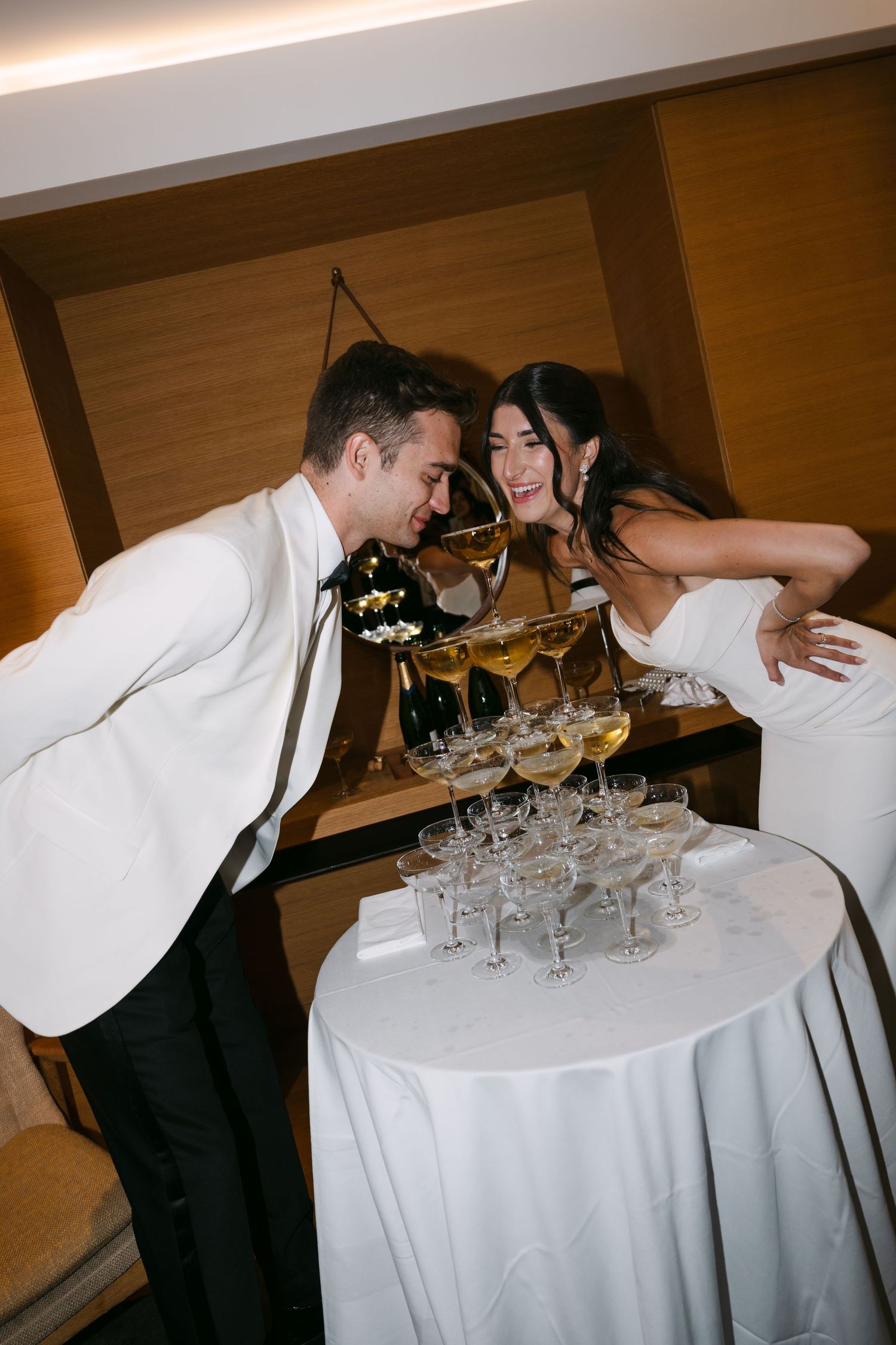 Bride and groom pouring champagne tower at elegant wedding reception.