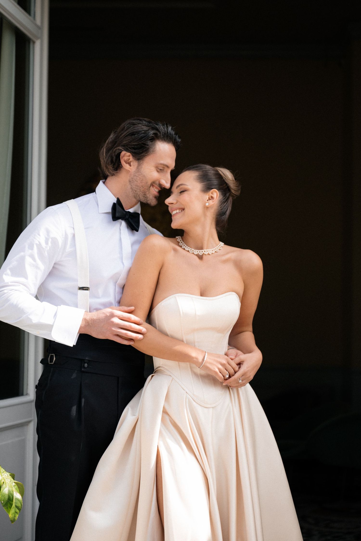 Elegant bride and groom in champagne and white wedding attire share a romantic outdoor moment.