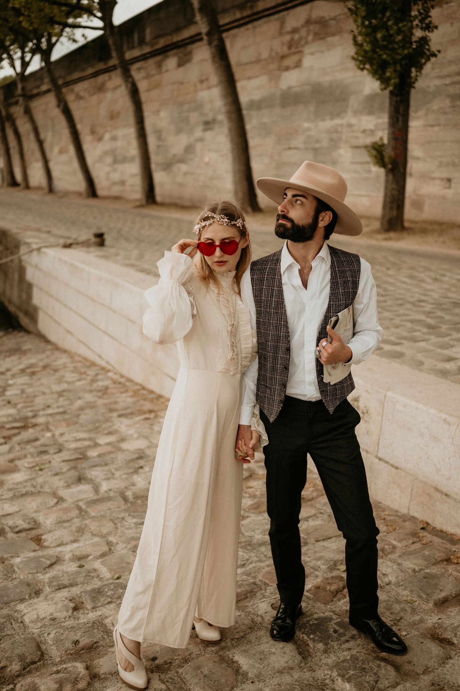 A romantic vintage-style photo of a couple posing against a stone wall in Paris.