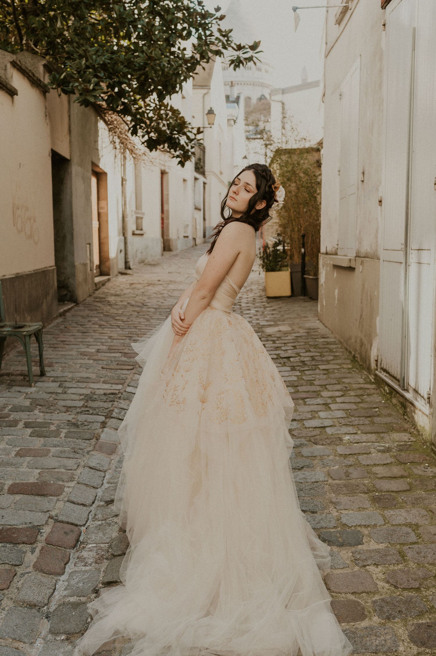 A romantic bridal portrait showing a flowing tulle gown against historic architecture and cobblestones.