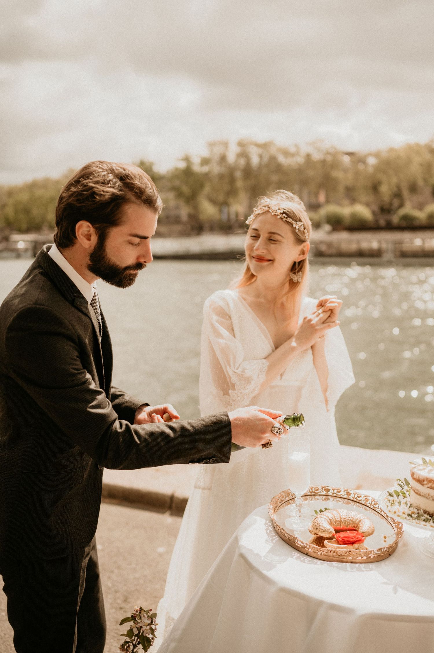 A couple cuts cake together during their romantic wedding celebration near a waterfront setting.