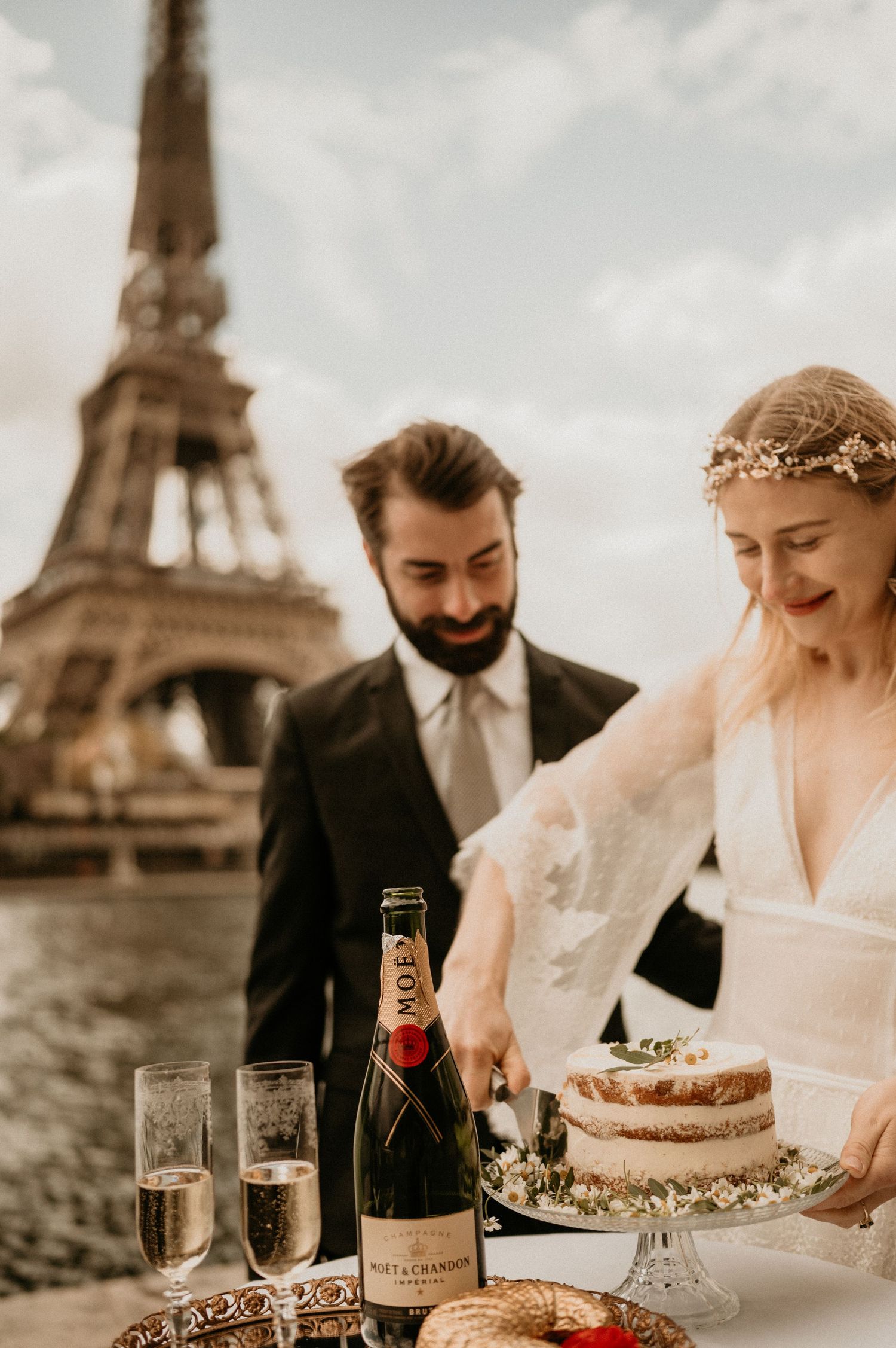 A romantic wedding celebration by the Eiffel Tower with champagne and a rustic wedding cake on display.