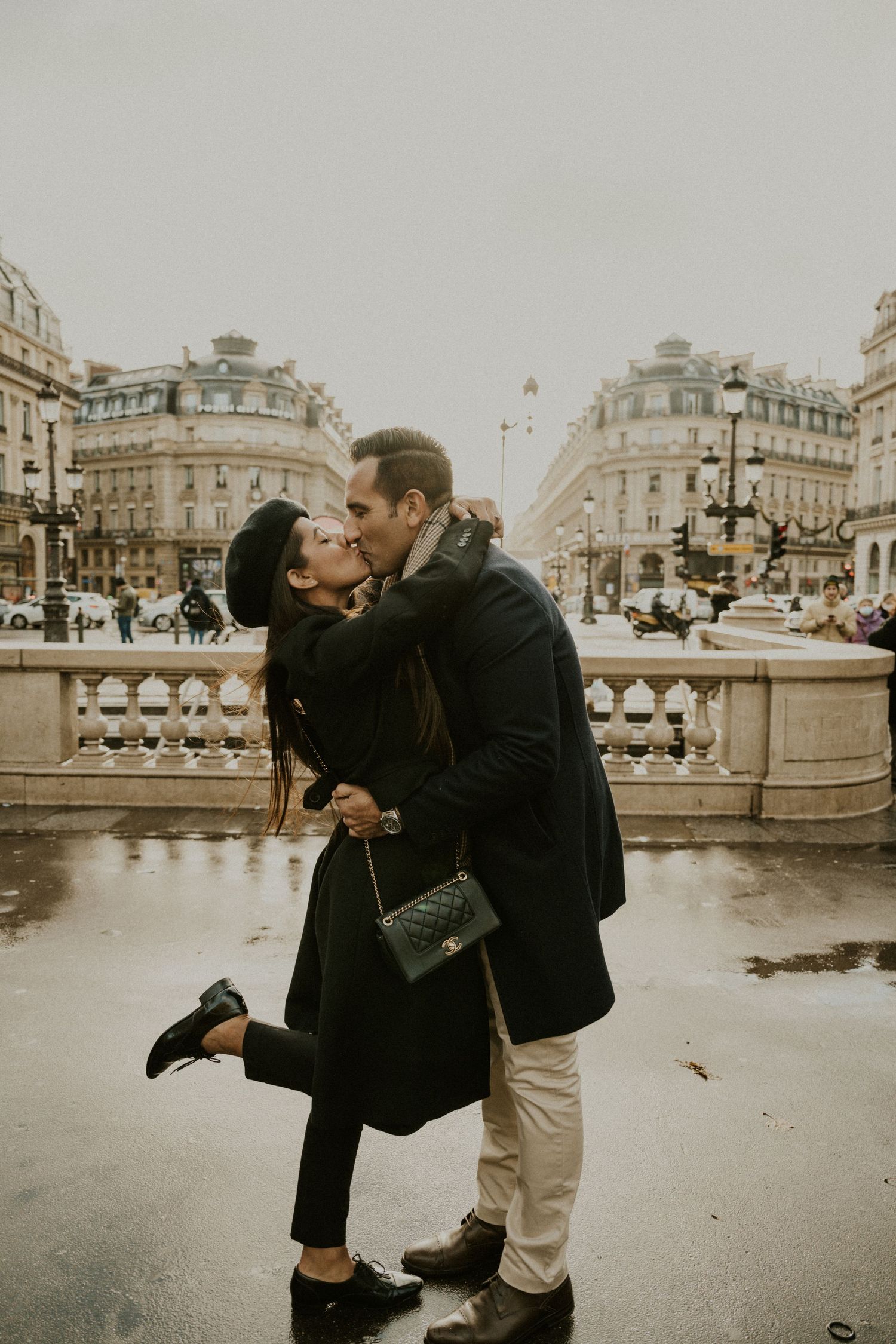 Romantic winter moment on a rainy day in Paris with classic Haussmann architecture in the background.