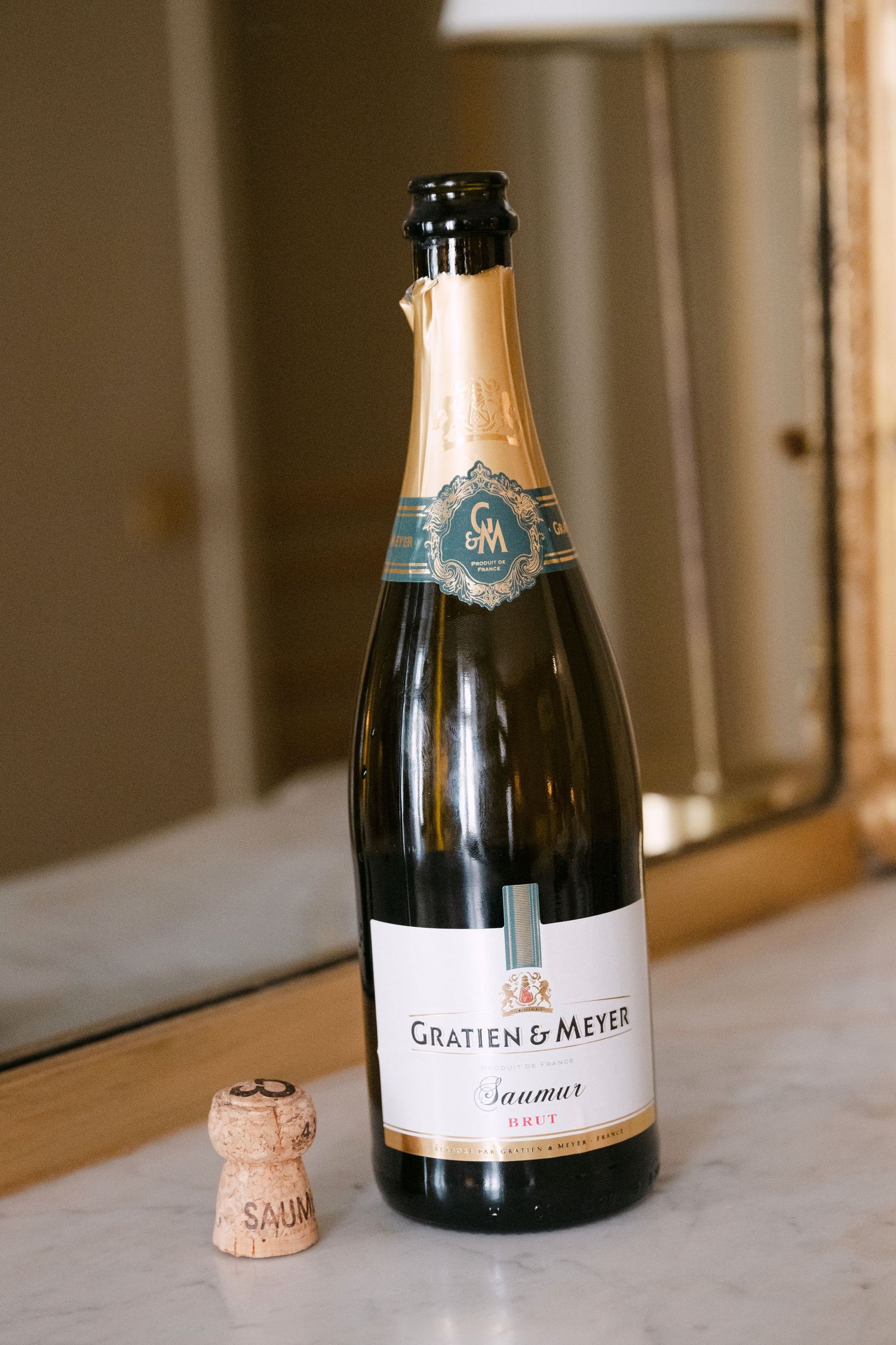 A series of champagne bottles with cork closures arranged in a row on a white marble surface.