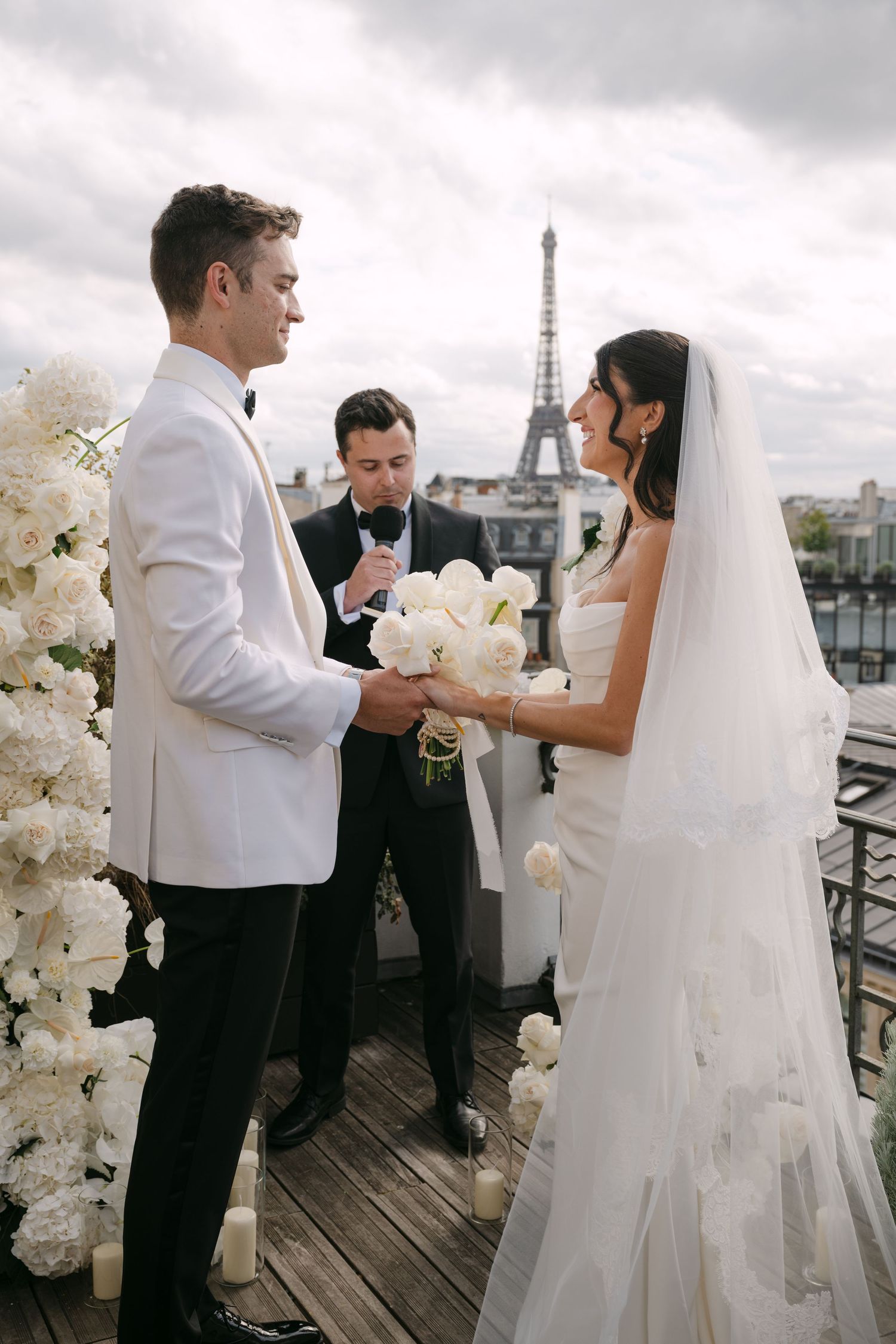 A romantic wedding ceremony takes place on a rooftop terrace in Paris with the iconic Eiffel Tower visible in the background.