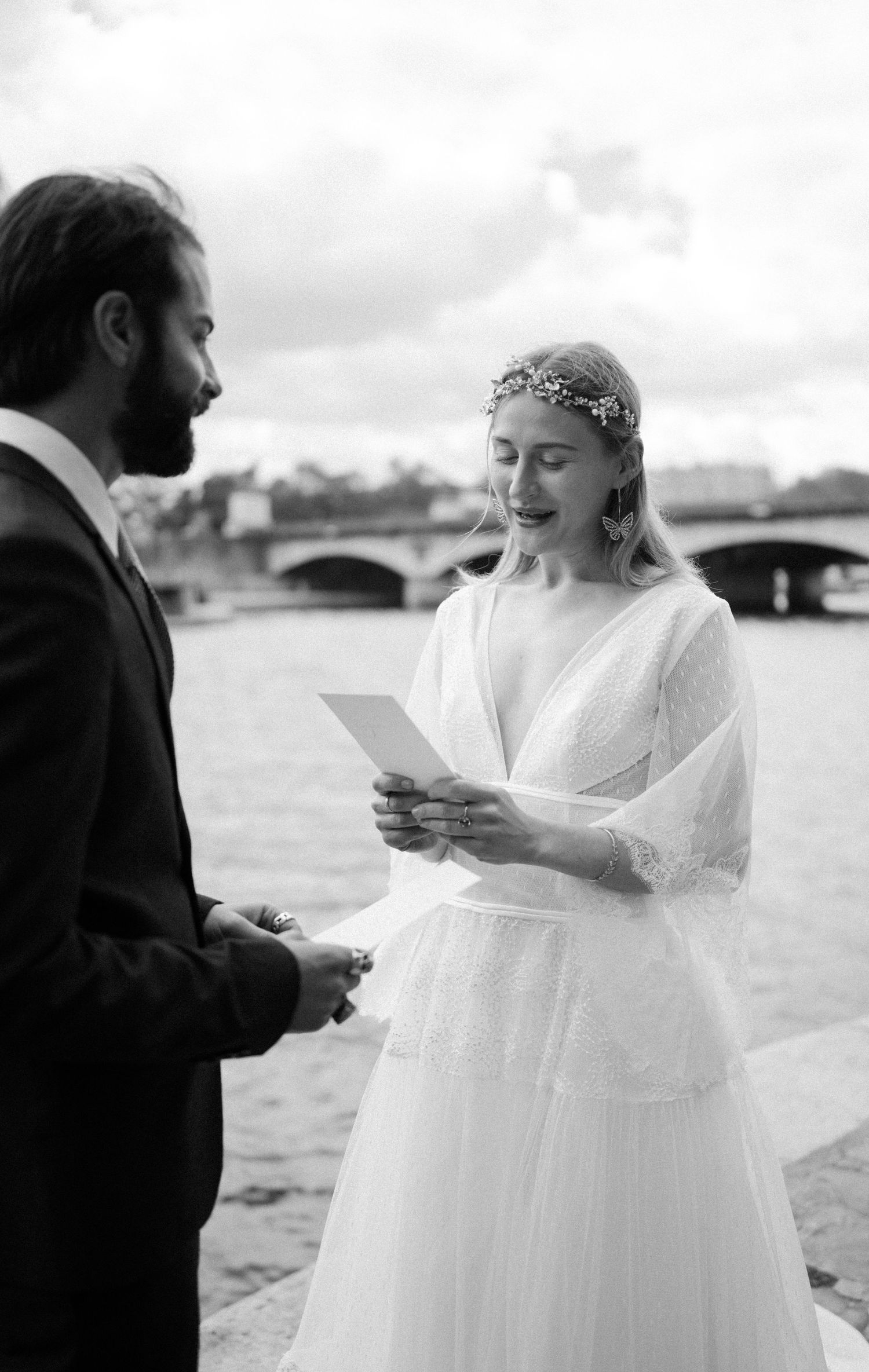 Black and white photo of wedding ceremony by Seine River with couple reading vows.