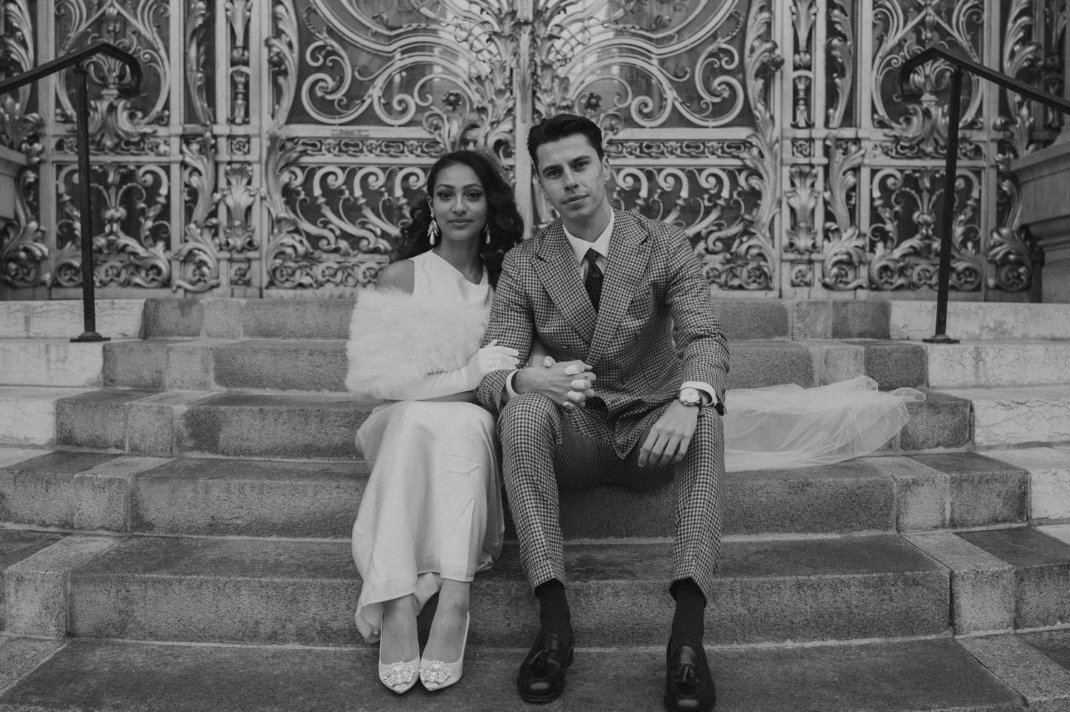 Classic black and white wedding photo of couple sitting on stone steps.