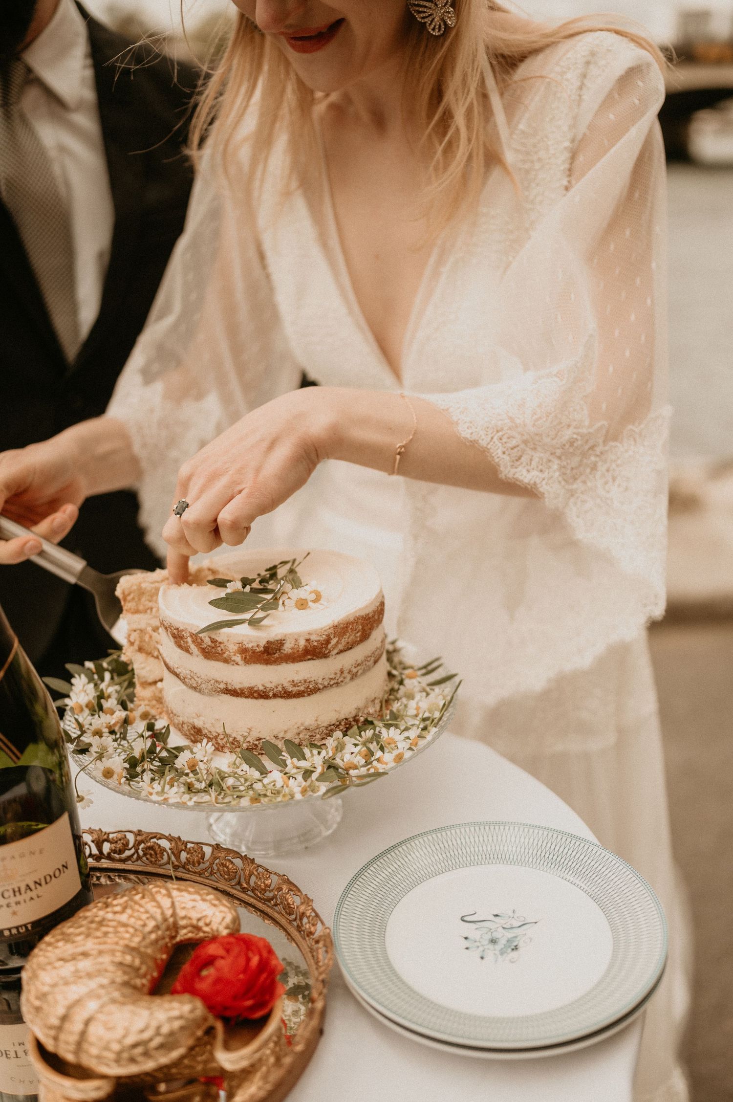 An intimate wedding cake cutting moment featuring a delicate white dress and rustic dessert display.