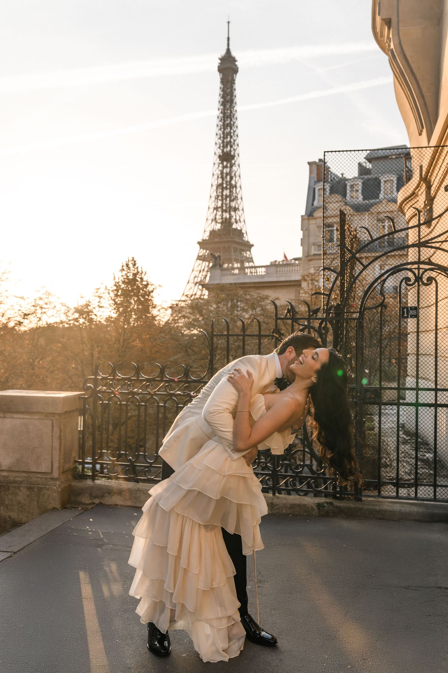 Couple sharing a romantic dip kiss in front of the Eiffel Tower at golden hour in Paris.