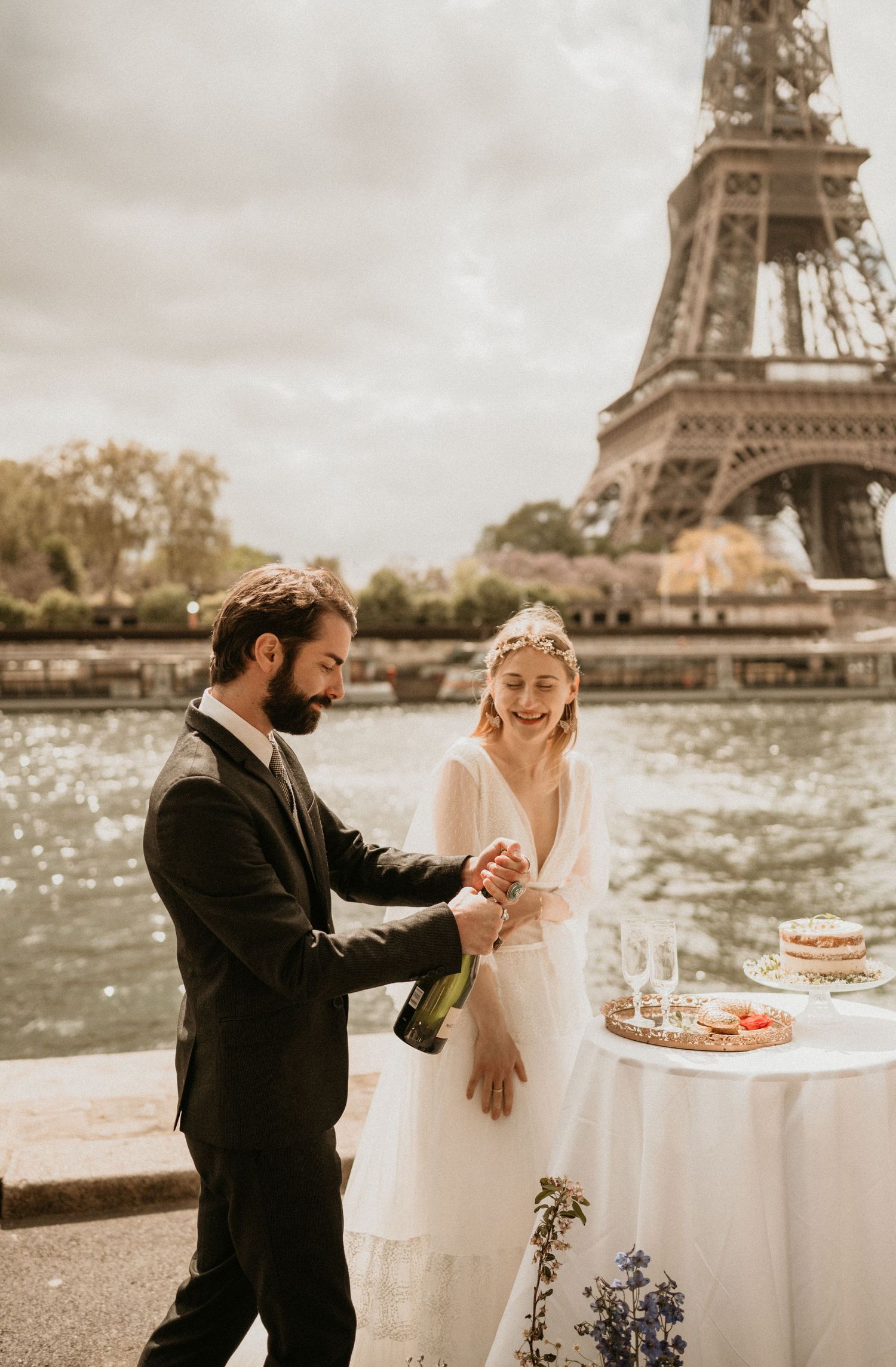 A couple opens champagne during their wedding celebration with the Eiffel Tower in the background.