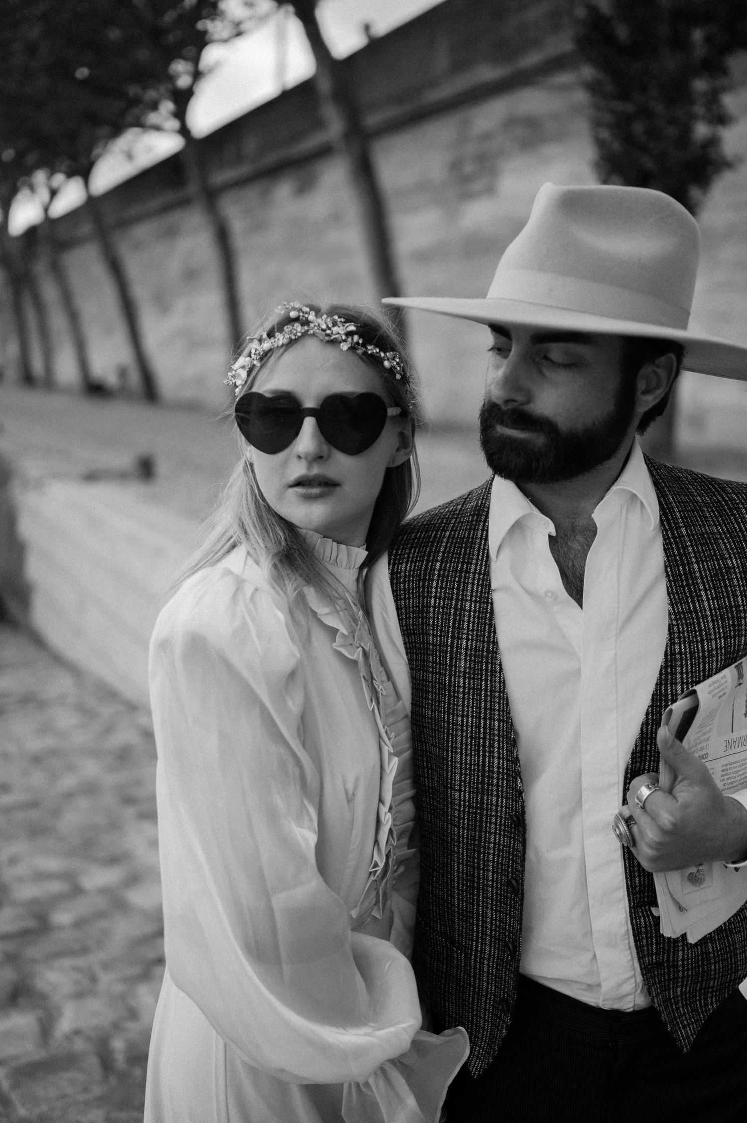 An artistic black and white photo of a couple in retro clothing against a textured wall backdrop.
