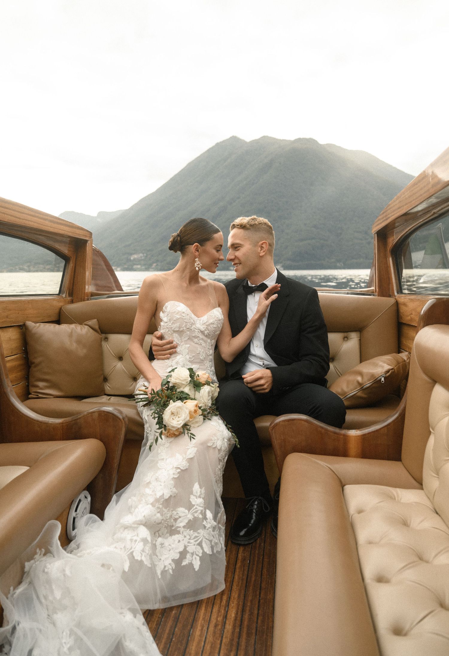 A couple sharing an intimate moment in a vintage wooden boat with luxurious leather seating.