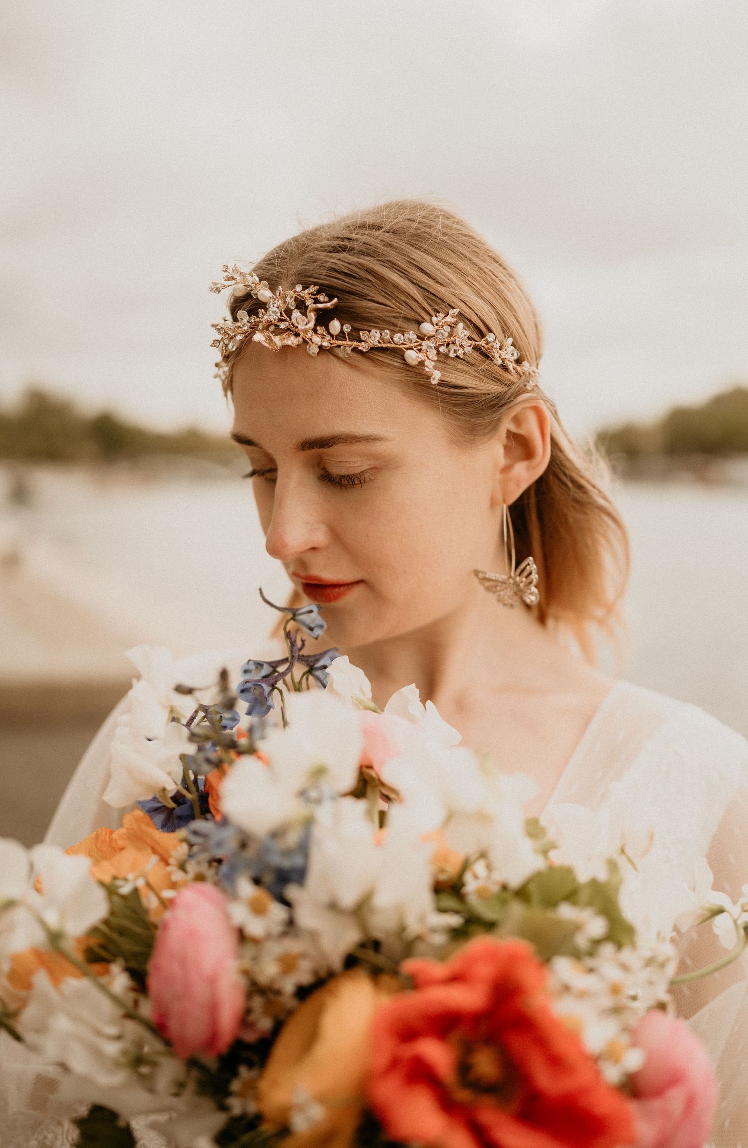 A close-up portrait of a bride wearing a delicate flower crown and holding a vibrant bouquet.