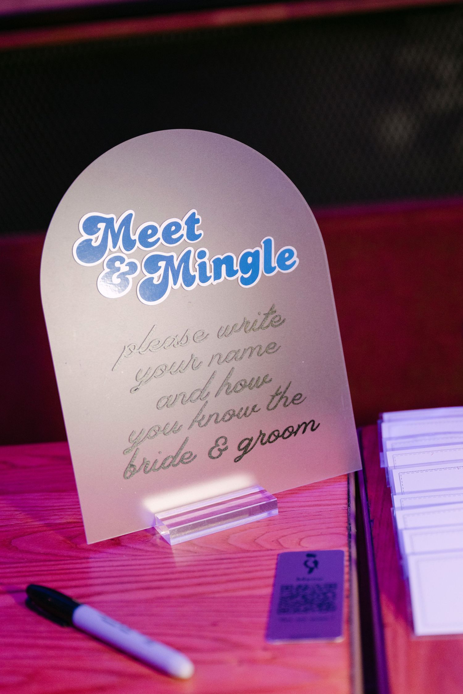 Frosted acrylic Meet and Mingle wedding sign asking guests to write their names.