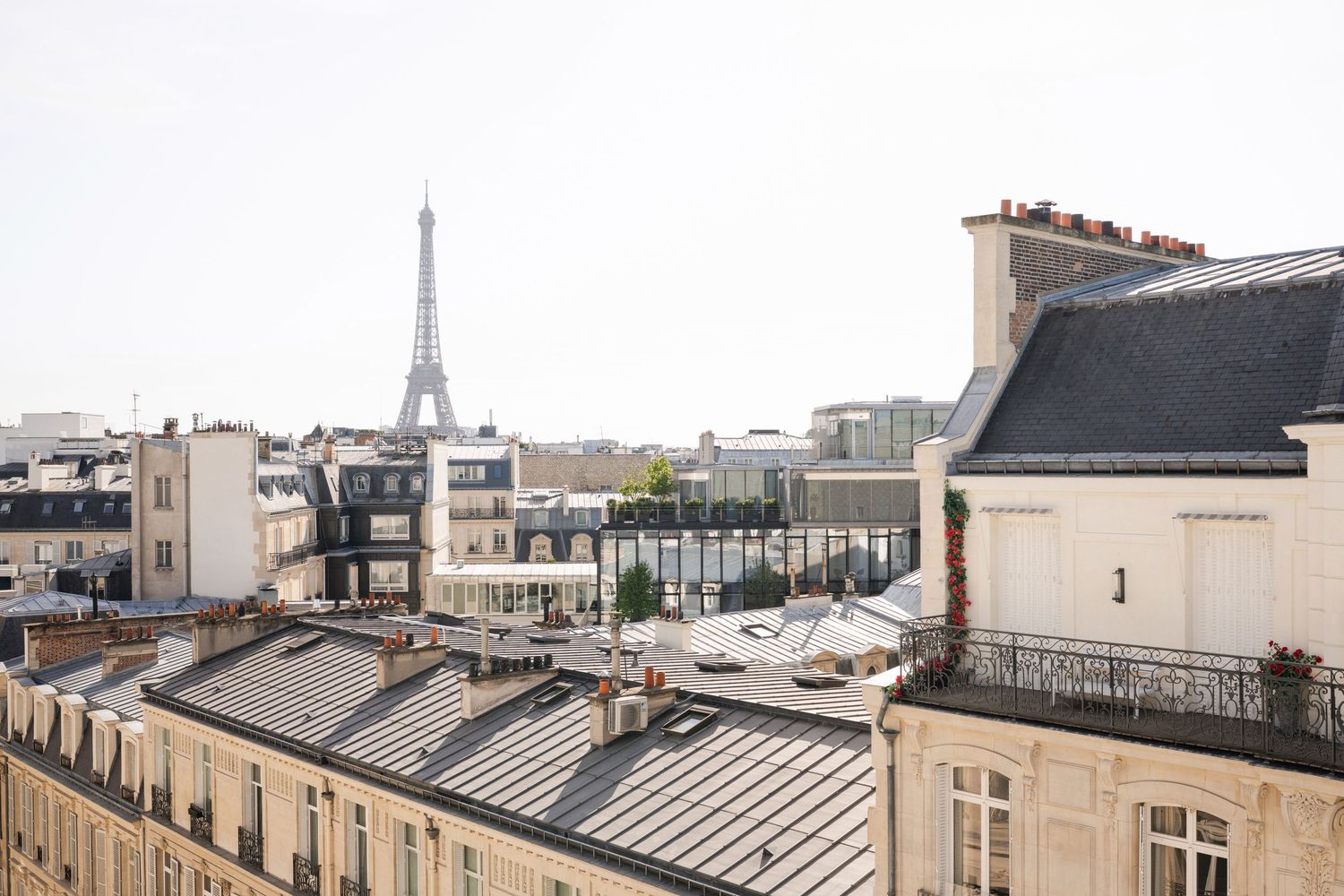 Rooftop view of Paris with the Eiffel Tower in the background, surrounded by classic Haussmann-style buildings.
