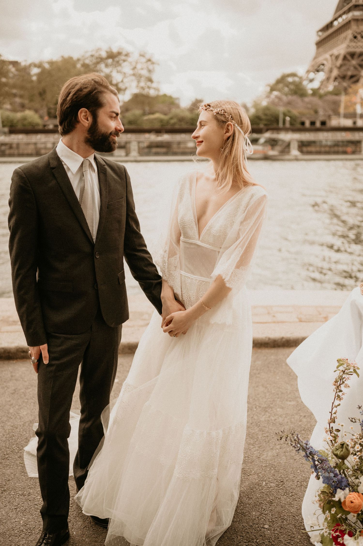 Wedding couple shares joyful moment near Eiffel Tower with bride in ethereal dress.