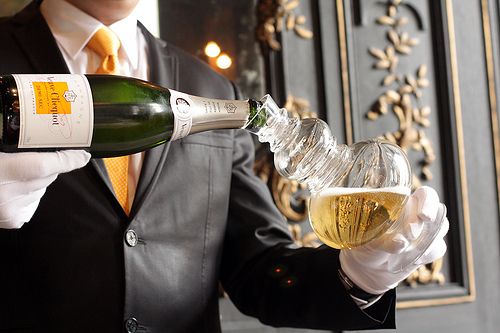 Elegant champagne service being poured from bottle to glass in a luxury setting.