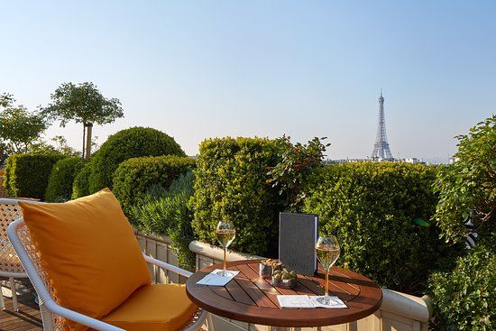 Luxurious rooftop lounge with orange cushions and Eiffel Tower views in Paris.
