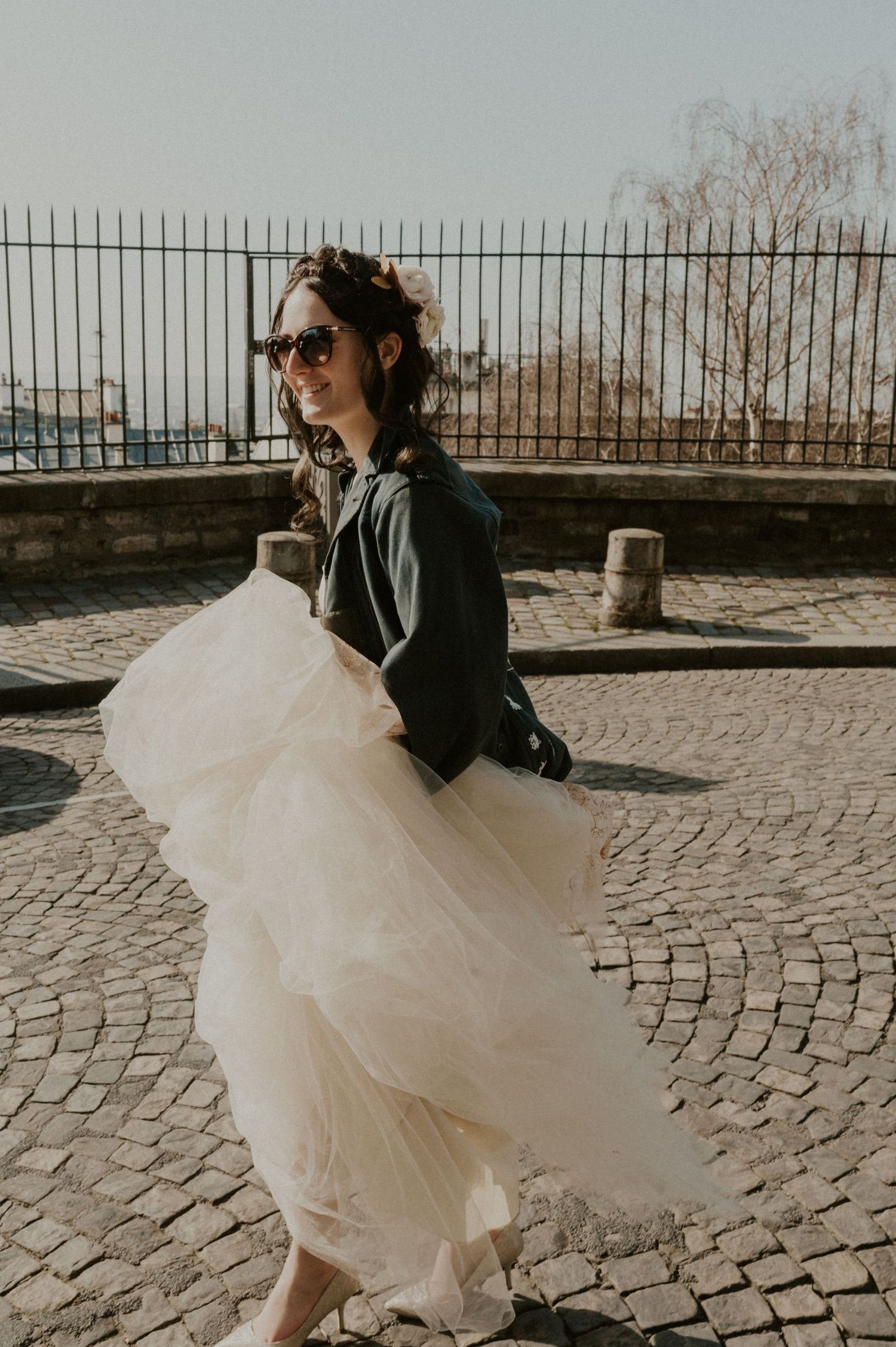 Edgy street style mixing a black leather jacket with ethereal white tulle against a stone backdrop.