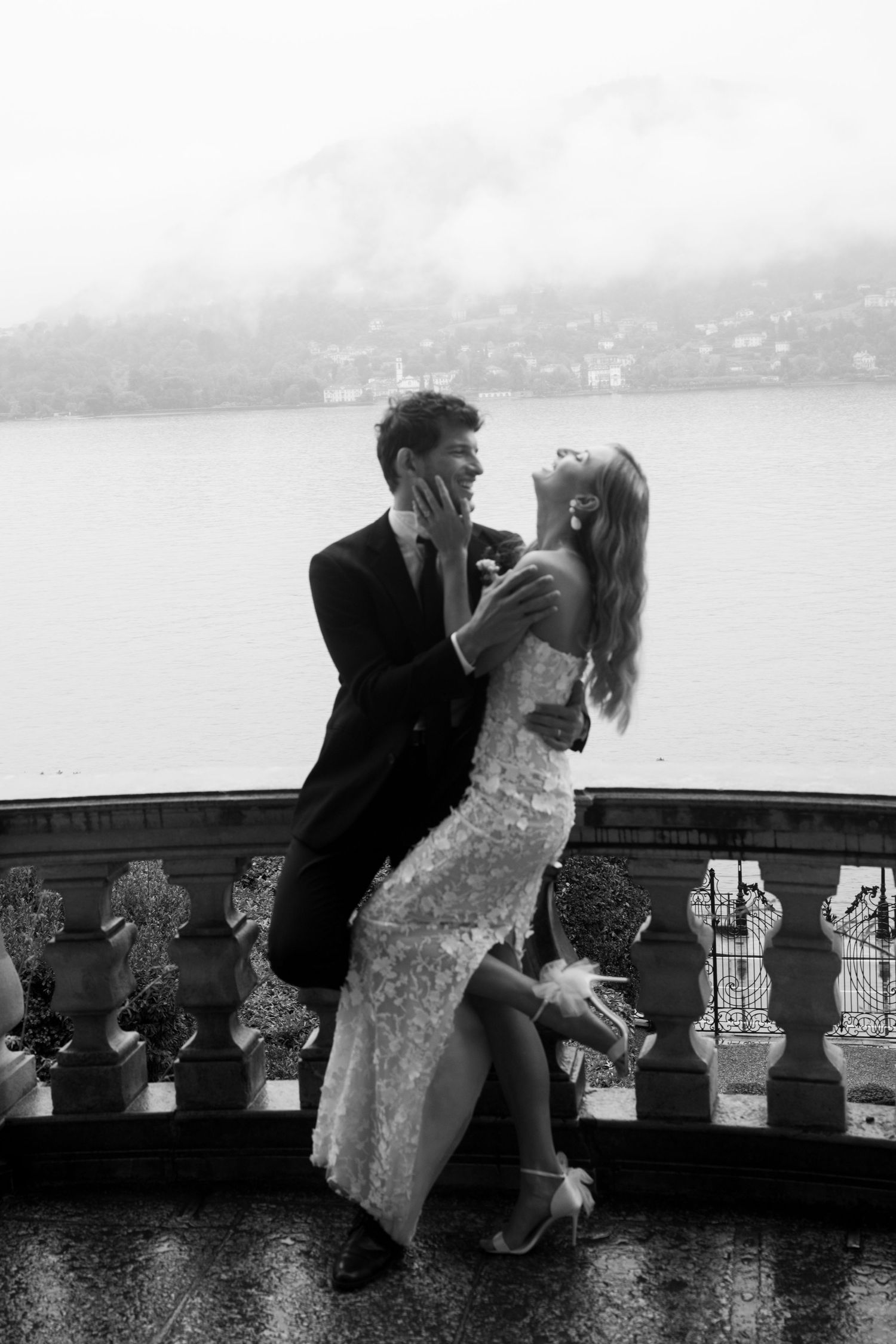 A couple shares a special engagement moment on a scenic cliffside overlooking a misty bay.