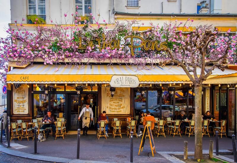 Charming Parisian cafe with blooming purple flowers and outdoor seating area.