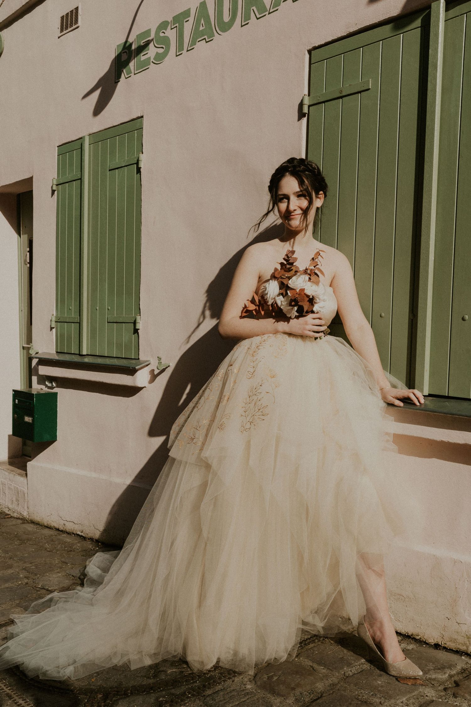 Artistic bridal portrait outside a French restaurant with vintage green shutters.
