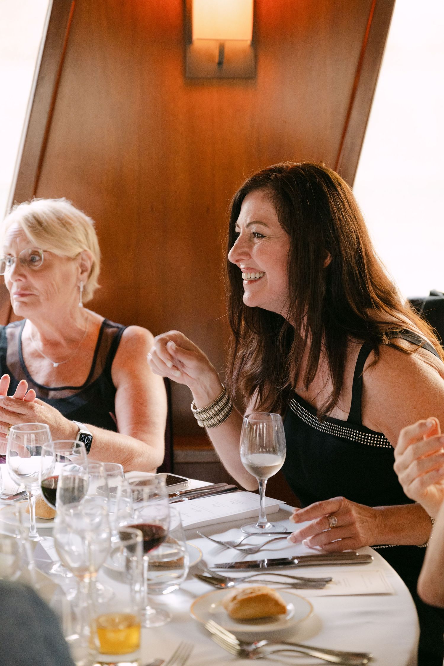 People enjoying conversation and drinks at an elegant dinner party with wine glasses and place settings.